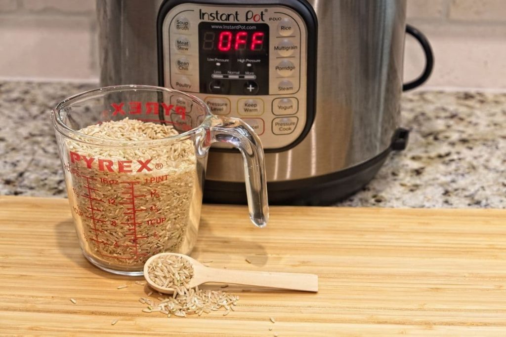 instant pot with a cup of rice in foreground